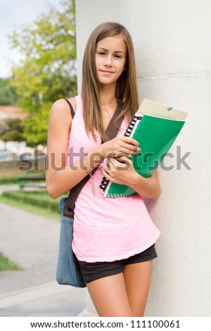 Back to school, cute young student girl with deep summer tan holding exercise books.