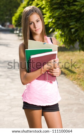 Back to school, cute young student girl with deep summer tan holding exercise books.