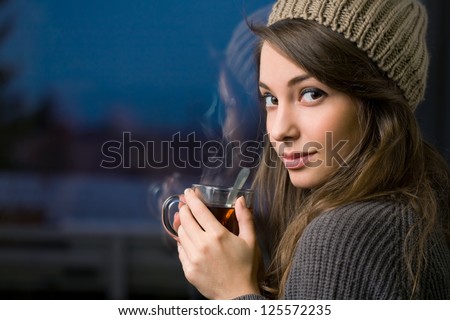 Gorgeous young brunette woman holding mug of hot tea.