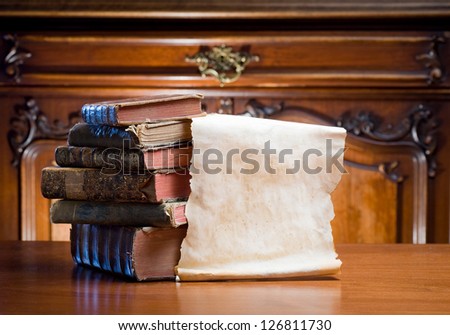 Old worn paper scroll with copy space next to antique books.
