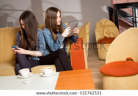Two girls getting lost in and separated by their mobile devices.