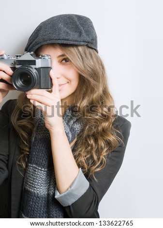 Portrait of very fashionable young brunette with retro film camera.