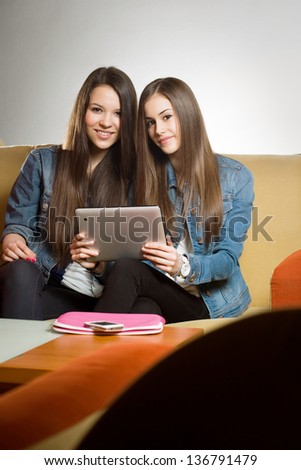 Portrait of a two beautiful teen girls having fun together with tablet computer.