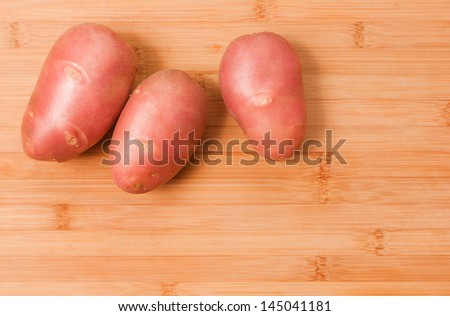 Fresh big raw potatoes on a wooden cutting board, with copy space.