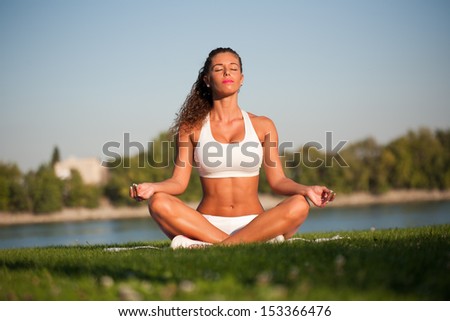 Tranquil moment, very fit young woman in relaxing yoga seat outdoors.
