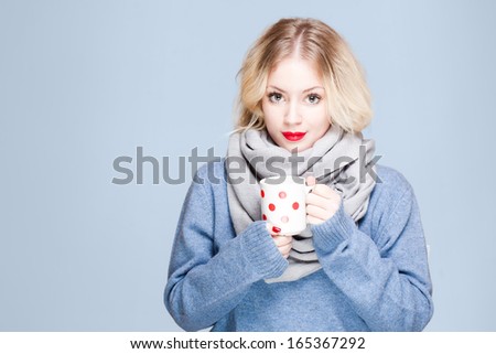Portrait of blond beauty in winter clothes holding mug of hot beverage.
