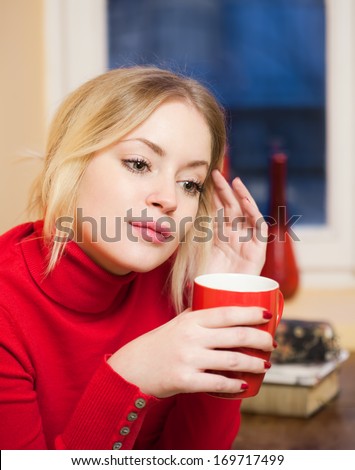 Portrait of a cute blond girl with a cup of hot beverage.