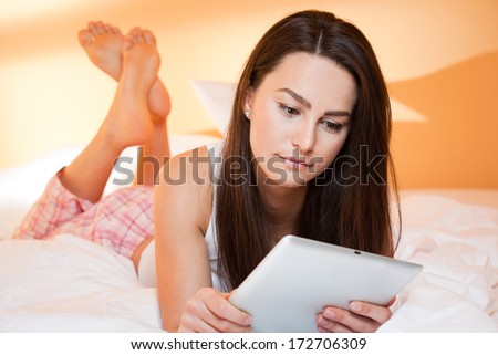 Gorgeous young brunette woman browsing with a tablet computer.