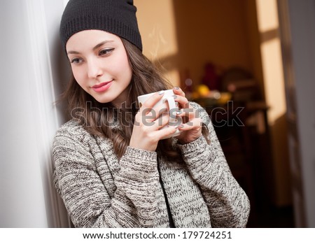 Portrait of a gorgeous young brunette woman relaxing with mug of hot beverage.