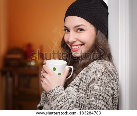 Portrait of a gorgeous young brunette woman holding mug of hot beverage.