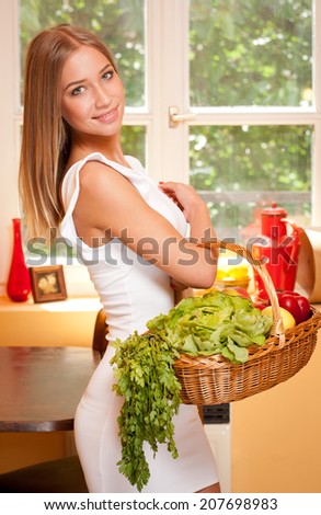 Fit gorgeous young blond woman holding wicker basket full of fresh vegetables.