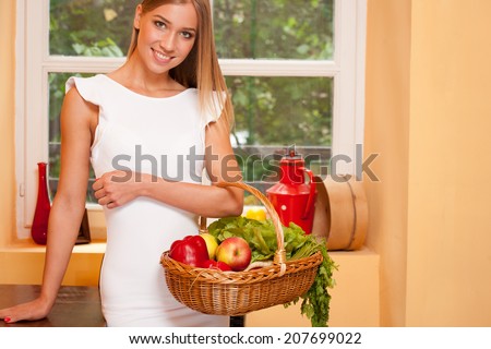 Portrait of a beautiful young blond woman with basket full of healthy groceries.