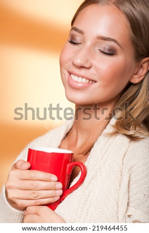 Beautiful young blond woman with mug of hot beverage.
