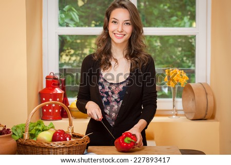Young brunette beauty in the kitchen with large basket of vegetables and fruits.