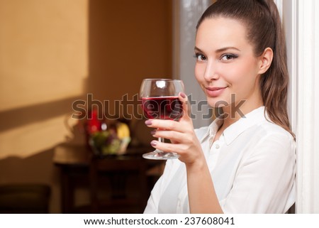Portrait of a beautiful young brunette woman holding a glass of fine wine.