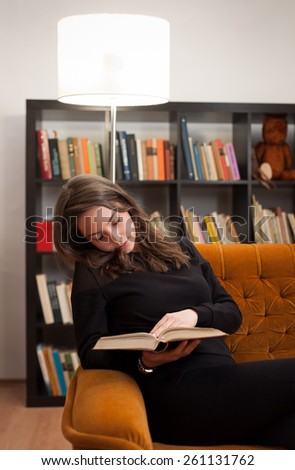 Portrait of young brunette beauty reading in comfort.