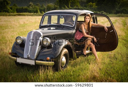 stock photo Beautiful young brunette posing with black old timer car