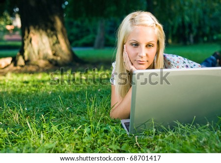 Beautiful young blond using laptop outdoors in nature.