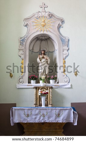Church interior, small altar with sculpture of Jesus Christ and flowers.