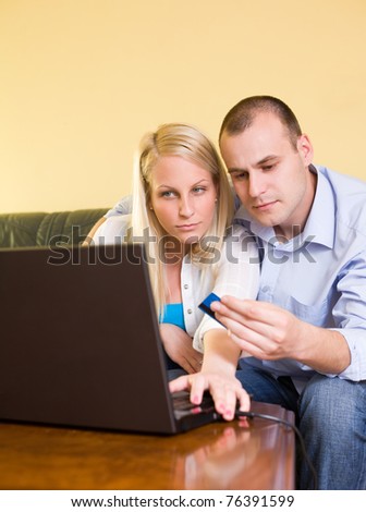 Young couple shopping online using credit card and a laptop at home.
