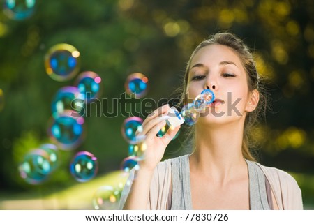 As easy as blowing bubbles, beautiful young brunette making soap bubbles outdoors.