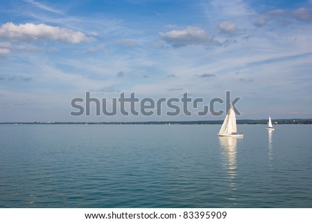 Sailing away on blue waters with strip of land behind.
