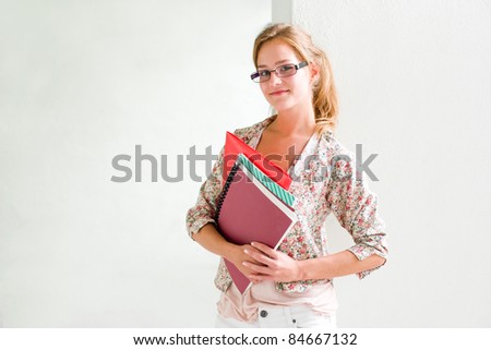 Portrait of cute young student girl with folder and exercise books.
