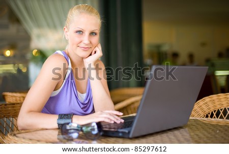 Portrait of beautiful young blonde woman being happy about findings through her laptop
