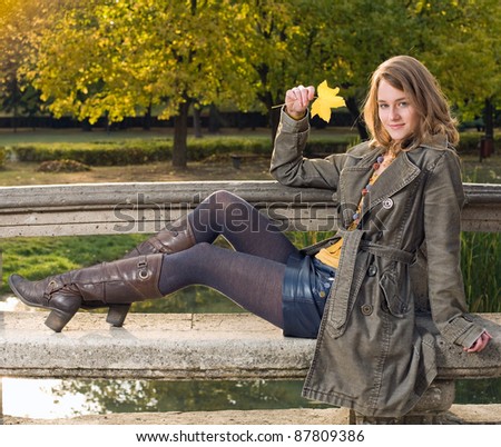 Full figure portrait of beautiful young woman in the park at fall.