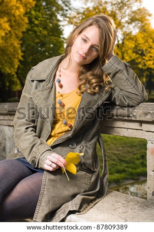 Beautiful young fashionable woman posing in autumn park.