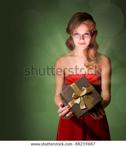 Half length portrait of beautiful blond holding gift box with creative lighting.