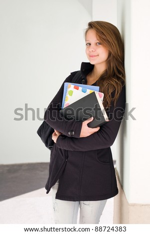 Half length portrait of a cute young smiling student with exercise books.