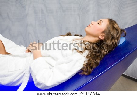 Gorgeous young brunette woman enjoying special design UV light relaxing at spa.