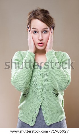 half length portrait of young brunette woman with very surprised facial expression.