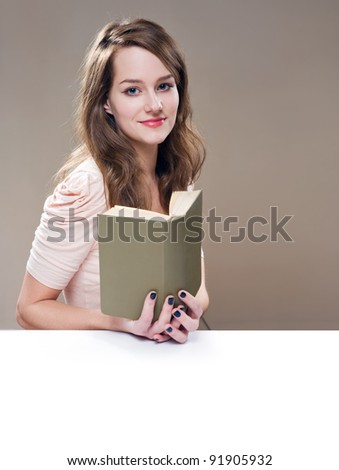 Portrait of beautiful relaxed young brunette woman holding a book, with white copy space.