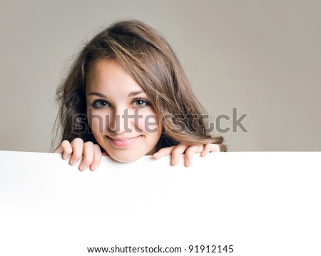Beautiful young brunette girl holding blank white sign with copy space.