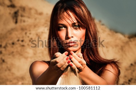 redhead woman outdoor portrait  hands full of sand, summer hot day, front view, small amount of grain added