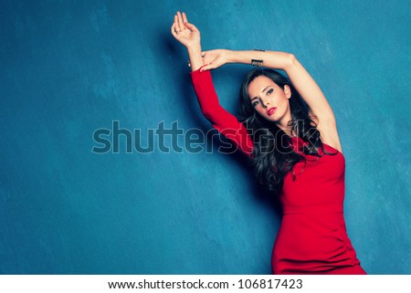 beautiful elegant woman in red dress on blue wall studio shot