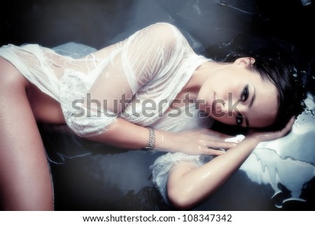sensual beautiful woman in white wet shirt resting in water