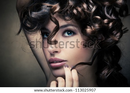 sensual brunette woman with shiny curly silky hair studio shot