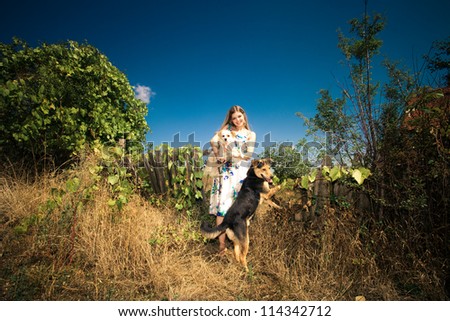 young woman in elegant silky dress with two cute dogs at countryside autumn sunny day