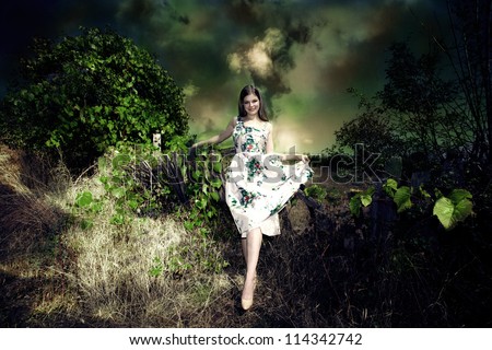 smiling young woman fairy like in elegant dress in dark green environment