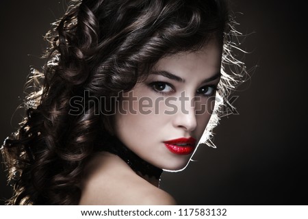 sensual young woman with shiny curly hair and red lips portrait in studio