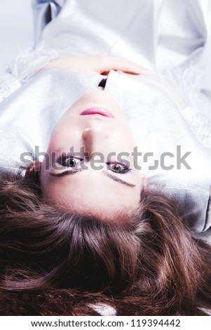 young elegant woman in silver dress lie on the floor studio shot