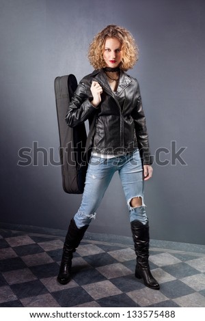 teen girl with her violin in leather jacket and blue jeans studio shot