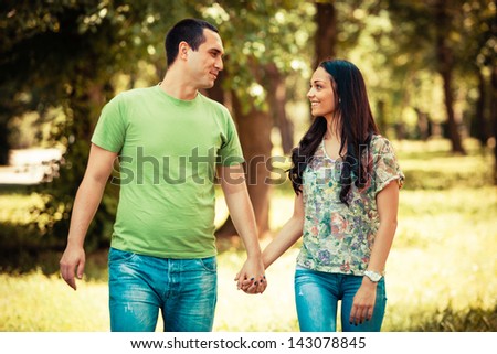 young smiling couple walk in park summer day