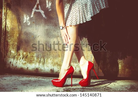 Woman Legs In Red High Heel Shoes And Short Skirt Outdoor Shot Against Old Metal Door