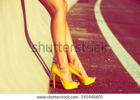 woman tan legs in high heel yellow shoes outdoor shot  summer day