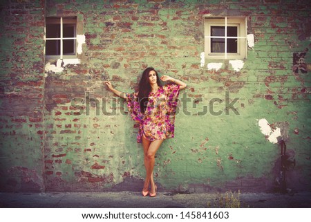 woman in colorful summer dress lean on old brick wall outdoor shot summer day