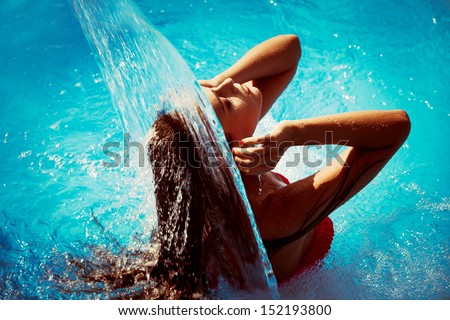 young woman refresh in pool under waterfall, retro colors